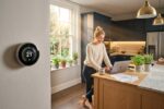 Person reviewing lower utility bills at home with energy-saving light bulbs and thermostat in background