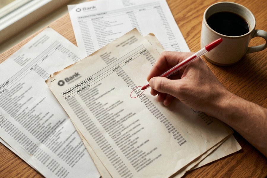 Person reviewing bank statements and credit card charges on laptop for subscription audit